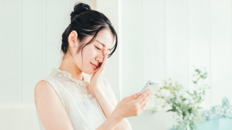 スマホを見て思い悩む女性
